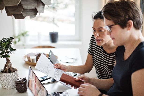 زوجان مثليان يناقشان الفواتير المالية أثناء استخدام الكمبيوتر المحمول على الطاولة