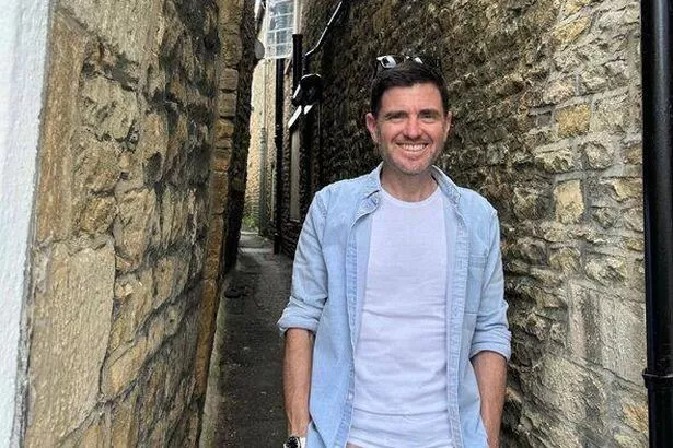يقف Steffan Rhys في واحدة من TORES التاريخي في Stow-on-the-Wold ، والأزقة الضيقة بين المباني تقريبًا بما يكفي للوقوف في