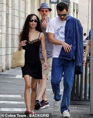 قام بتشويش قميص الدنيم الأزرق على كتفيه وأكمل المظهر مع المدربين البيض ونظارات شمسية أسود