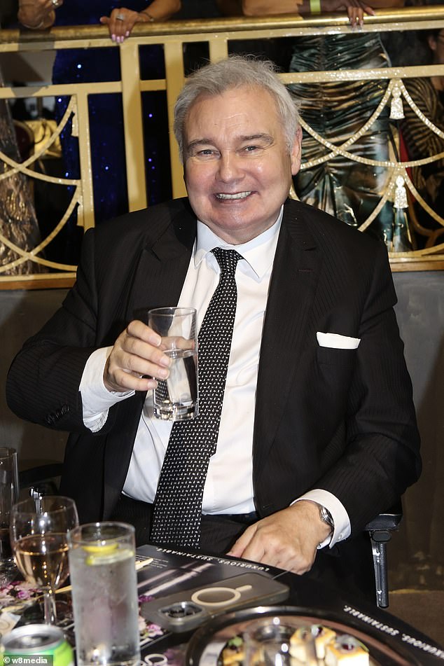 بدا Eamonn dapper في بدلة سوداء مع ربطة عنق البولكا البيضاء لقضاء الليل الفخم أثناء اختيار كوب من الماء في المكان