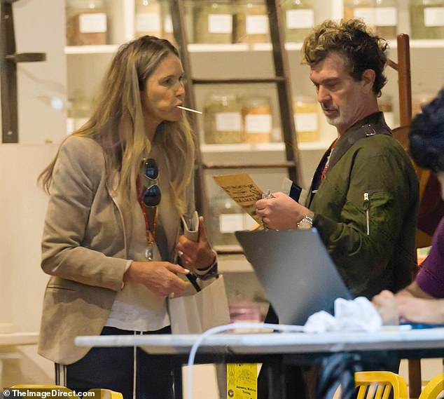 لقد تم إكسسواراته بقميص رمادي وزوج من الأحذية الرياضية البني وأمسك حقيبة حقيبة