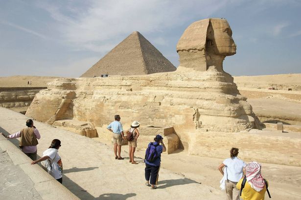 جيزا ، مصر - 13 نوفمبر: يعجب السياح في أبو الهول بينما يلوح هرم خوفو خلف 13 نوفمبر 2004 في جيزا ، خارج القاهرة ، مصر. الأهرامات الثلاثة الكبيرة في الجيزة ، التي بناها الملك خوفو على مدار 30 عامًا حوالي 2550 قبل الميلاد ، هي من بين أكبر مناطق الجذب السياحي في مصر. (تصوير شون جالوب/غيتي إيمايز)