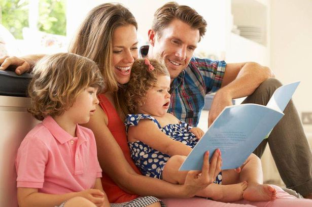 عائلة تجلس على الأرض تقرأ كتابًا.
