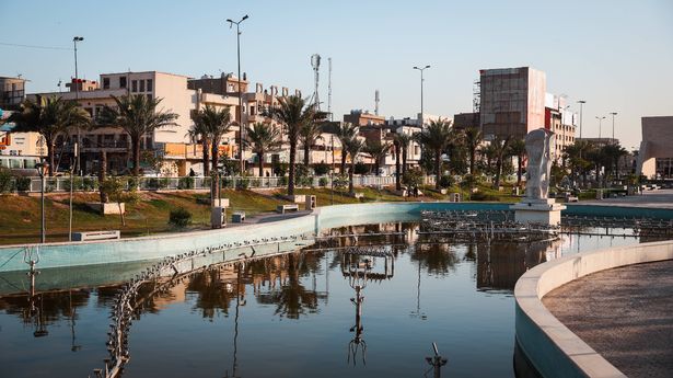 بغداد ، العراق - 22 مارس 2025: يستمتع الزوار بالجواء الهادئة لحديقة في بغداد ، ويعرضون أشجار النخيل وانعكاسات المياه الهادئة عند غروب الشمس.