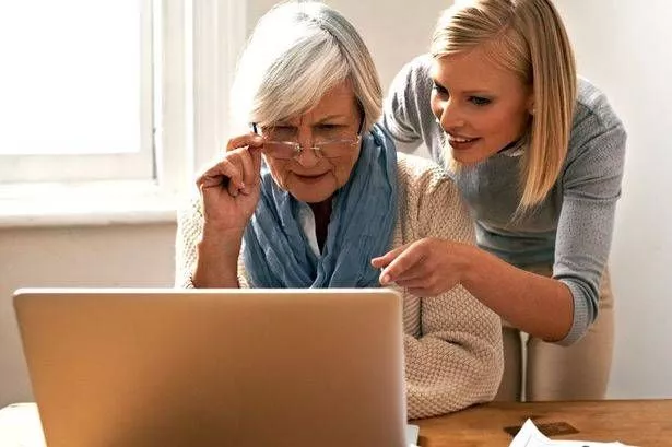 امرأة شابة تساعد والدتها في شيء تعمل عليه على الكمبيوتر