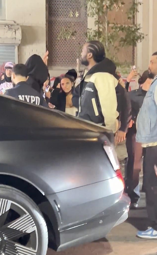 تُظهر اللقطات المتداولة عبر الإنترنت الفنان البالغ من العمر 37 عامًا وهو يقف واضعًا يديه خلف ظهره بينما تجمع حشد من الناس، متشككًا في تصرفات الضباط