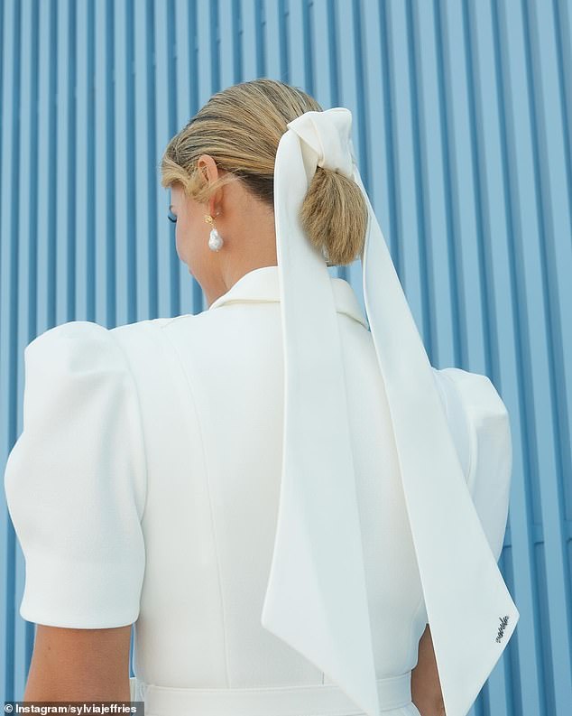 لقد أكملت مظهرها بزوج من الأحذية ذات الكعب العالي الأبيض والأقراط المتدلية من اللؤلؤ