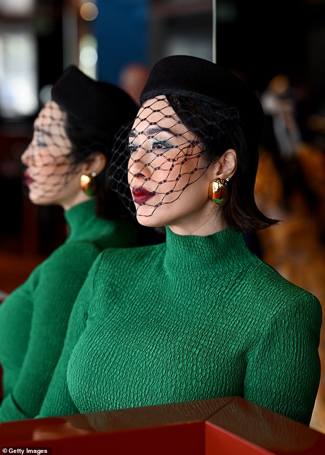 اختارت نسخة سوداء من القبعة الدائرية، والتي تتميز بحجاب شبكي على الجهة الأمامية يحجب وجهها. تناقضت القبعة السوداء مع فستانها الأخضر الزاهي