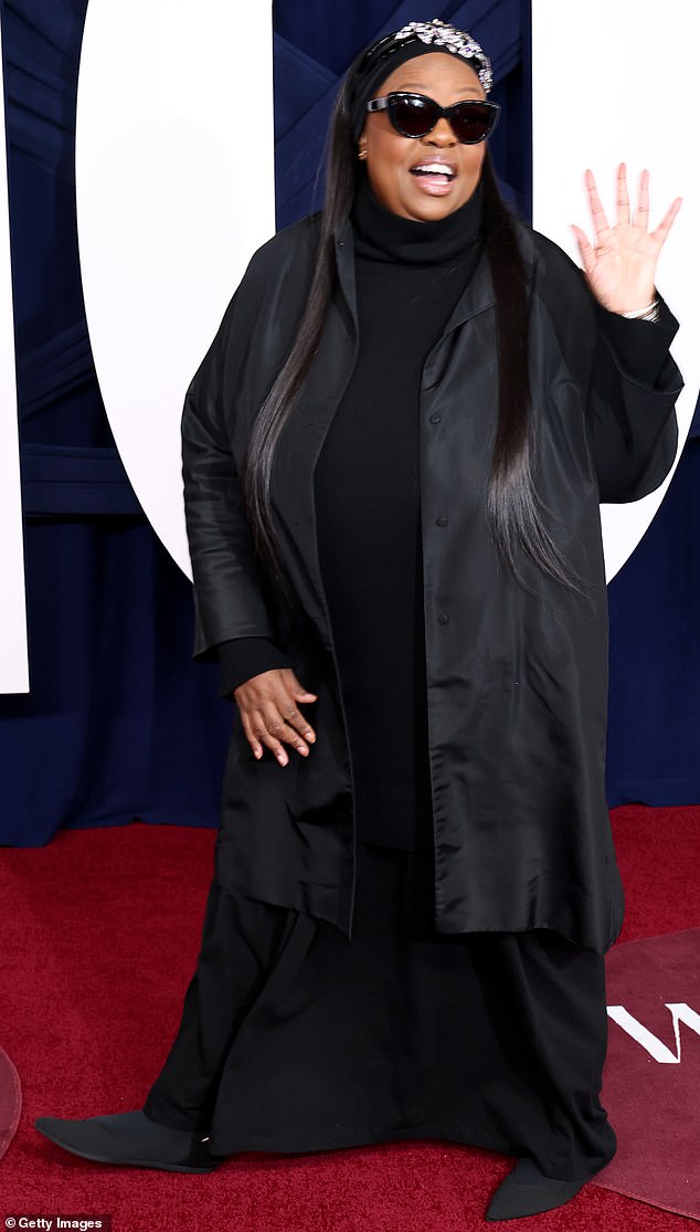 المكرم بات ماكغراث، أول فنانة مكياج تحصل على لقب سيدة في المملكة المتحدة، جعلت حضورها محسوسًا في ملابس كانت سوداء بالكامل باستثناء قبعتها البيضاء.