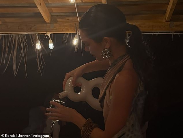 ارتدت الجزء العلوي مع تنورة ملفوفة بنية من الساتان وهي تقف أمام بالونات فضية ضخمة مكتوب عليها 