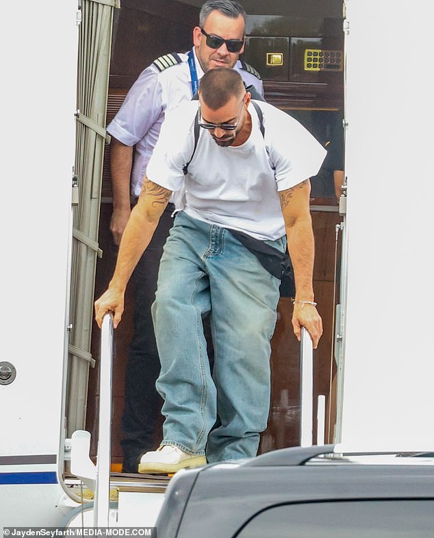 كان يرتدي أيضًا بنطال جينز أزرق فاتح فضفاض، بالإضافة إلى سترة ربطها حول خصره.