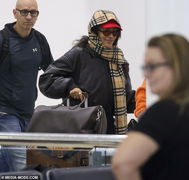 على الرغم من رغبتها في أن تمر دون أن يلاحظها أحد، يبدو أن الرحلة لم تزعج أوليفيا التي يمكن رؤيتها وهي تبتسم وهي تشق طريقها عبر المطار.