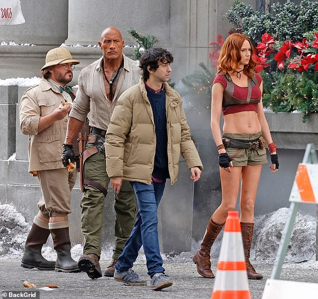 يبدو أن المجموعة، وجميعهم يرتدون الأزياء، يصورون مشهدًا على طراز عيد الميلاد خارج المبنى مع وجود ثلج مزيف على الأرض وأشجار صنوبر صغيرة مزينة بزخارف على الرصيف.