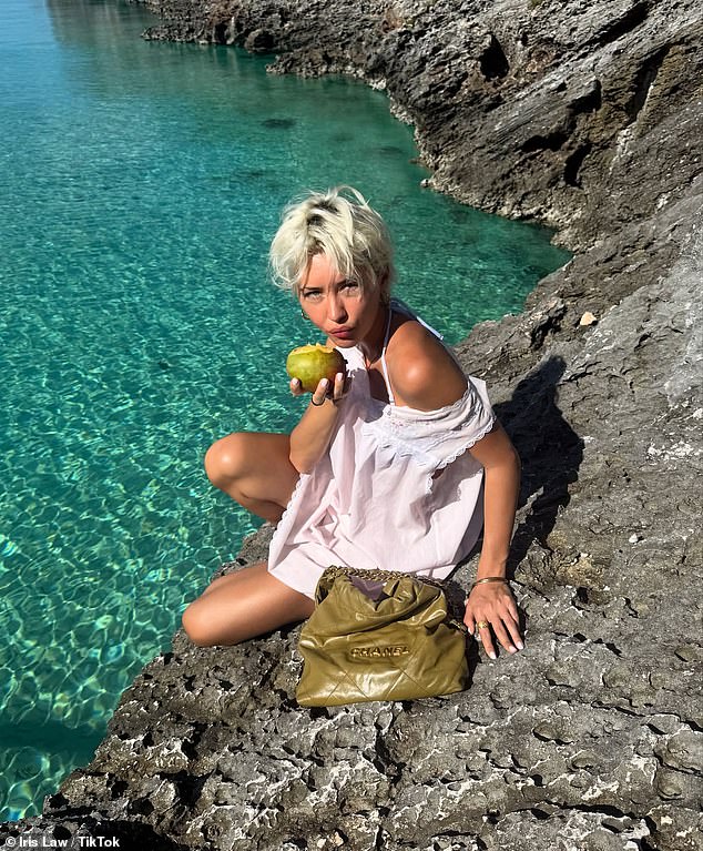 وقفت أيضًا على حافة منحدر صخري وهي تستمتع بأشعة الشمس وتشاهد المياه الزرقاء الصافية