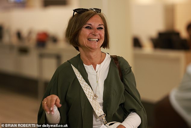 ابتسمت والدة توم بابتسامة كبيرة وهي تدفع أمتعتها أثناء الإجابة على أسئلة المراسلين والمصورين المجتمعين