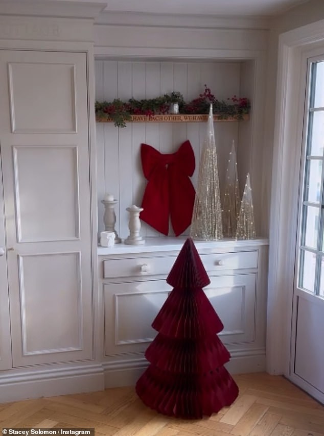 في نفس الغرفة، تمتلك الأم لخمسة أطفال شجرة عيد الميلاد من الورق الأحمر بقيمة 80 جنيهًا إسترلينيًا مع إكليل وقوس على رفوف كتبها