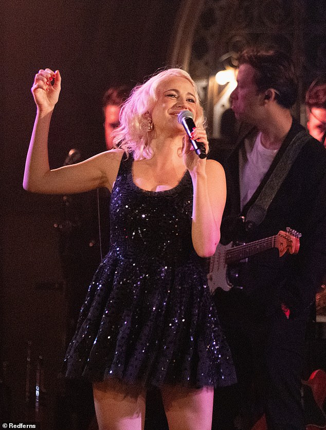 أثناء أدائها على المسرح، بدت مذهلة بفستان أسود قصير مزين بالترتر، يتميز بفتحة عنق واسعة وتنورة على شكل حرف A.