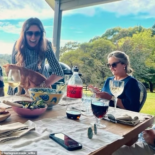 وفي الوقت نفسه، أظهرت الصورة الثانية سوزي تبدو أقل بريقًا، هذه المرة مرتدية فستانًا مربعًا باللونين الأبيض والأسود، وهي تضحك وهي تحاول إزالة قطة من طاولة الطعام.