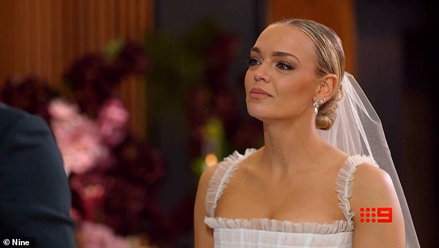 العروس أليسا فاي (في الصورة) والعريس ديفيد موموه يقفان جنبًا إلى جنب عند المذبح بينما يقوم المحتفل بتسليم النذر التقليدي