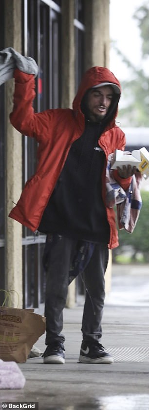 ظل النجم الطفل لمرة واحدة دافئًا في معطف أحمر فوق قميص من النوع الثقيل الأسود مع بنطال رمادي وحذاء رياضي أسود من Nike في يوم الشتاء