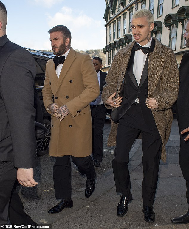 رجال بيكهام (في الصورة: ديفيد وروميو) جميعهم يتميزون بمظهر أنيق ويرتدون بدلات سوداء أنيقة تعلوها ربطات عنق ومعاطف طويلة باللون الرمادي ودرجات مختلفة من اللون البني.