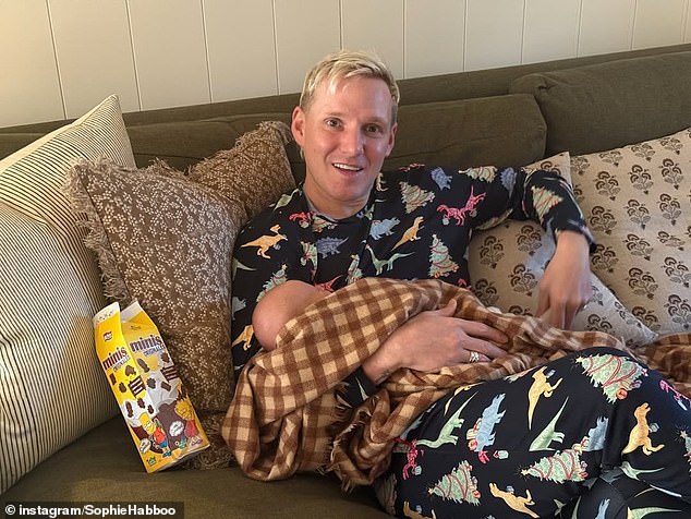 يظهر جيمي وهو يرتدي بيجامة احتفالية متطابقة بينما يحتضن ابنه الجديد بين ذراعيه المغطى ببطانية مربعات باللونين البني والبيج