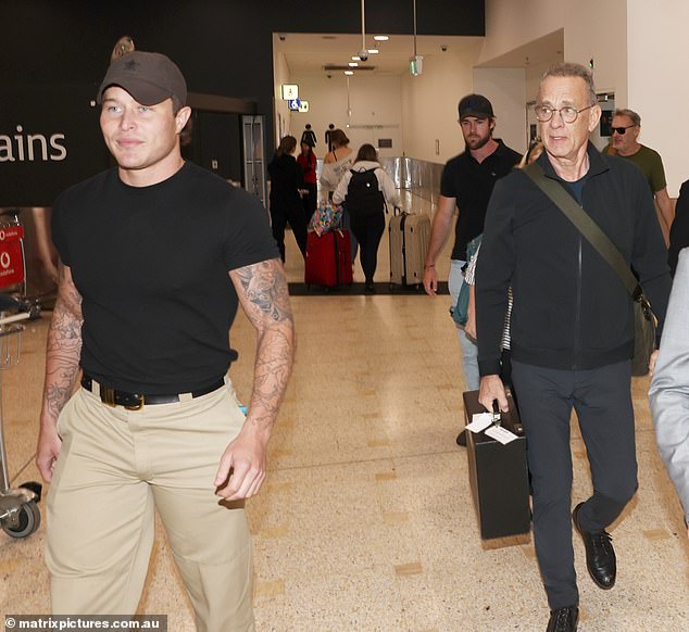 ظهر حارس الأمن ذو الأشرطة بشكل ملفت للنظر وهو يرتدي قميصًا أسود مناسبًا، والذي أظهر ذراعيه الموشومتين بشكل كبير والعضلات بشكل مثير للإعجاب