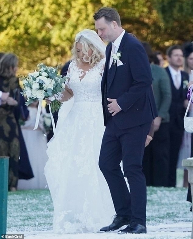 بدت ليلي مذهلة في فستان زفاف تقليدي من الدانتيل الأبيض مع طبقة مميزة عند خروجها من المكان وذراعها بذراع زوجها الجديد.