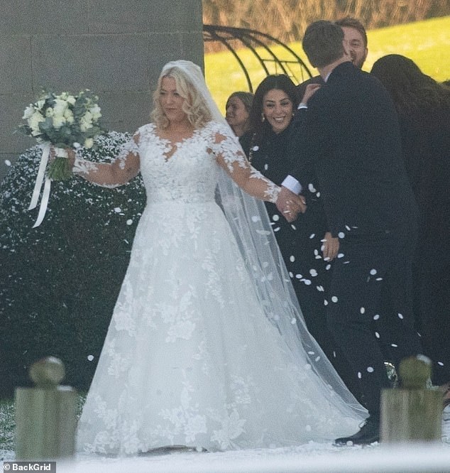 أمسكت ليلي بباقة من الزهور بينما كان الضيوف يمطرون الزوجين المتزوجين حديثًا بالحلويات