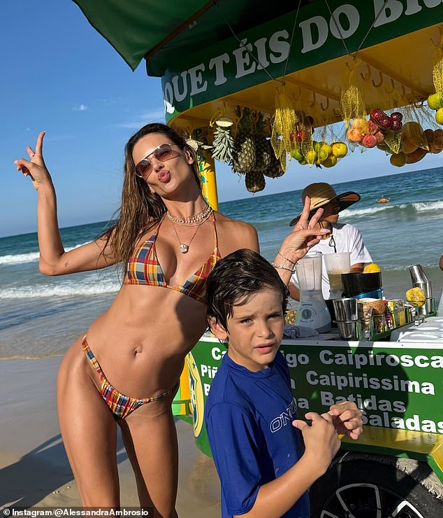 هنا تومض بعلامة السلام وهي واقفة بجوار عربة بار على الشاطئ