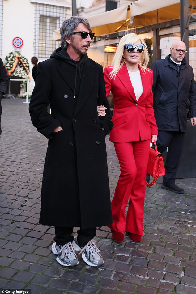 أضافت بوصات إلى إطارها مع الكعب العالي الأحمر وحملت أساسياتها في حقيبة يد جلدية من فيرساتشي