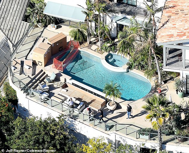 تحيط الآن صفوف من أشجار النخيل الشاهقة بحوض السباحة في منزل بيت في لوس أنجلوس، مما يمنح الفناء الخلفي إحساسًا بملاذ فاخر لقضاء العطلات