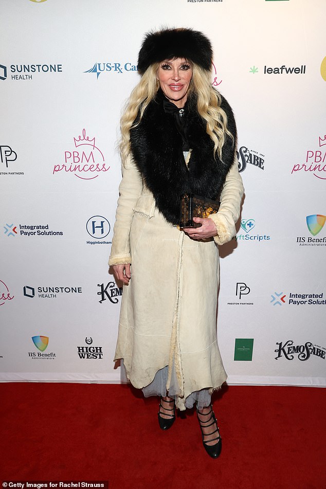 كانت ترتدي قبعة من الفرو الأسود ومعطفًا طويلًا من جلد الغزال الأبيض مع شال من الفرو الأسود ملفوف حول رقبتها