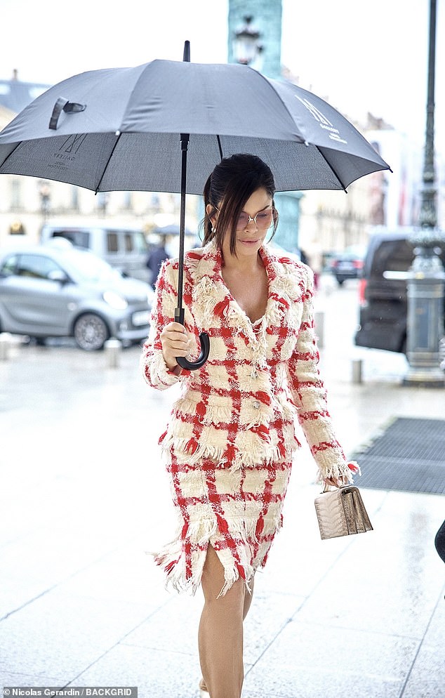 أضافت بوصات إلى إطارها مع زوج من الأحذية البيضاء ذات الكعب المدبب من Jimmy Choo وحملت أساسياتها في حقيبة بيضاء من Schiaparelli