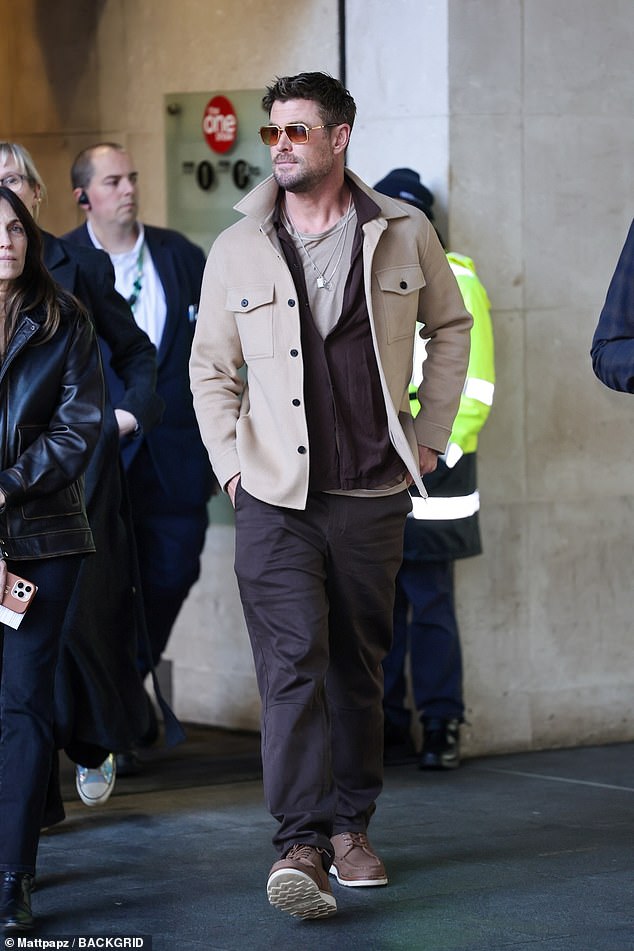 قطع كريس شكلاً أنيقًا يرتدي سترة بنية اللون وسروالًا بنيًا أثناء خروجه من استوديوهات بي بي سي