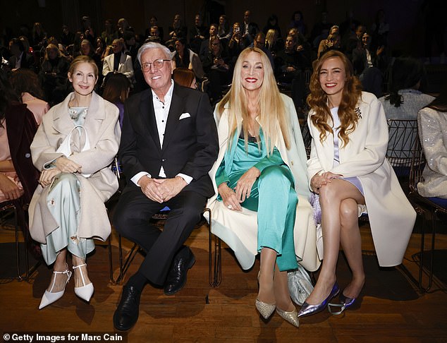 يتميز فستان كيلي بأكمام منتفخة وأطراف غير متماثلة، مع حقيبة كتف بيضاء وحذاء بكعب عالي.