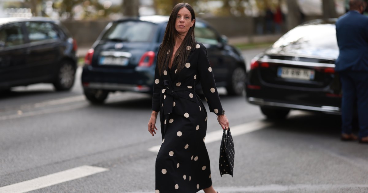 شوهدت إحدى ضيوف أسبوع الموضة وهي ترتدي أقراطًا مرصعة بالألماس مستديرة، وفستانًا أسود متوسط الطول بأكمام طويلة مع نمط منقط أبيض، وطية صدر محززة، وحزام ربطة عنق؛ سوار من الذهب؛ وساعة من الذهب الوردي والأسود من رولكس؛ خاتم من الذهب؛ وحقيبة يد سوداء مستطيلة بنمط نقاط بيضاء؛ وأحذية مدببة سوداء اللون، أيضًا بنمط نقاط البولكا البيضاء قبل عرض أزياء إيلي صعب للملابس النسائية لربيع وصيف 2025 كجزء من أسبوع الموضة في باريس في 28 سبتمبر 2024 في باريس، فرنسا.