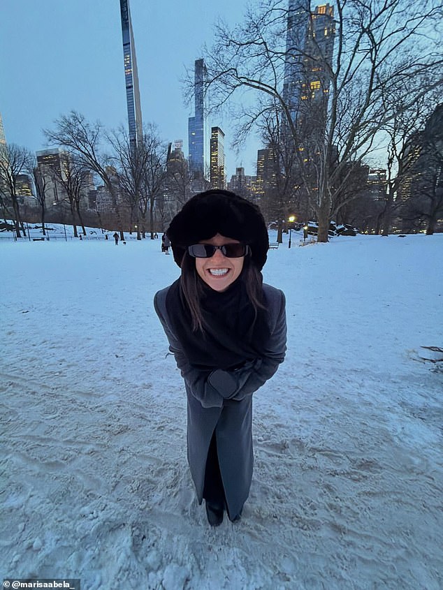 استمتعت ماريسا بالثلج وهي تبتسم وترتدي معطفًا طويلًا من الجلد مع ياقة من الفرو وقبعة ناعمة متطابقة، نسقتها مع نظارة شمسية مستطيلة.