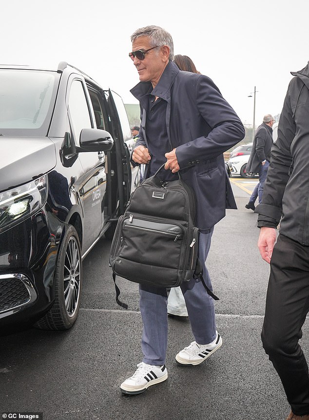 قام جورج بتصميم شخصية ذكية مرتديًا قميص بولو باللون الأزرق الداكن نسقه مع بنطال رمادي وسترة داكنة أنيقة ويحمل حقيبة ظهر سوداء كبيرة