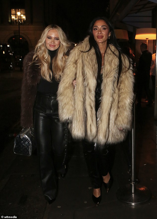 نيكول، 47 عامًا، ترتدي معطفًا من الفرو الصناعي باللونين الكريمي والبني فوق مشد من الجلد الأسود وبنطلون ضيق يشبه الجلد