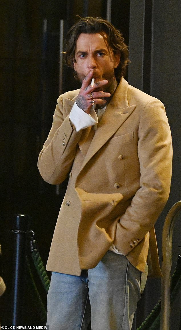 قام بيت بتصفيف خصلات شعره الداكنة للخلف ودخن خارج المكان الفخم